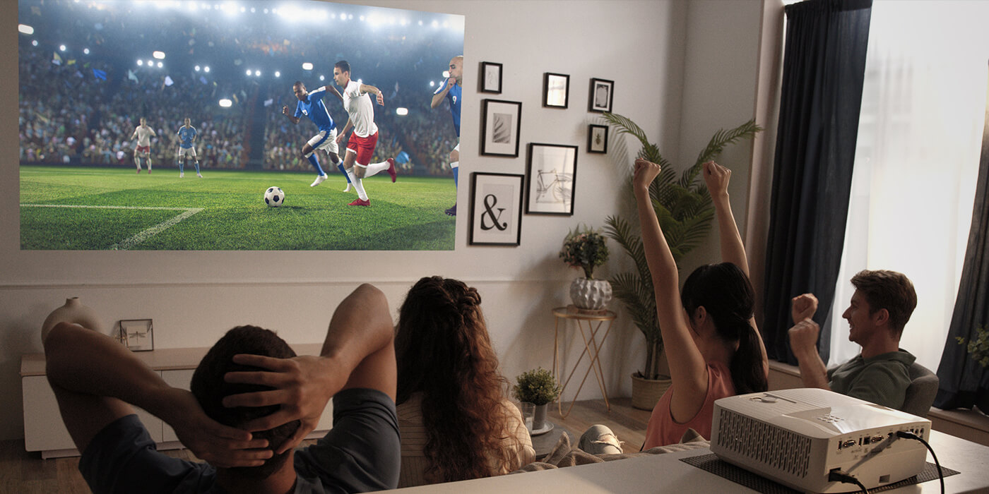 A group of people watching football using an Optoma projector. Some are celebrating and others are unsatisfied with the results. 