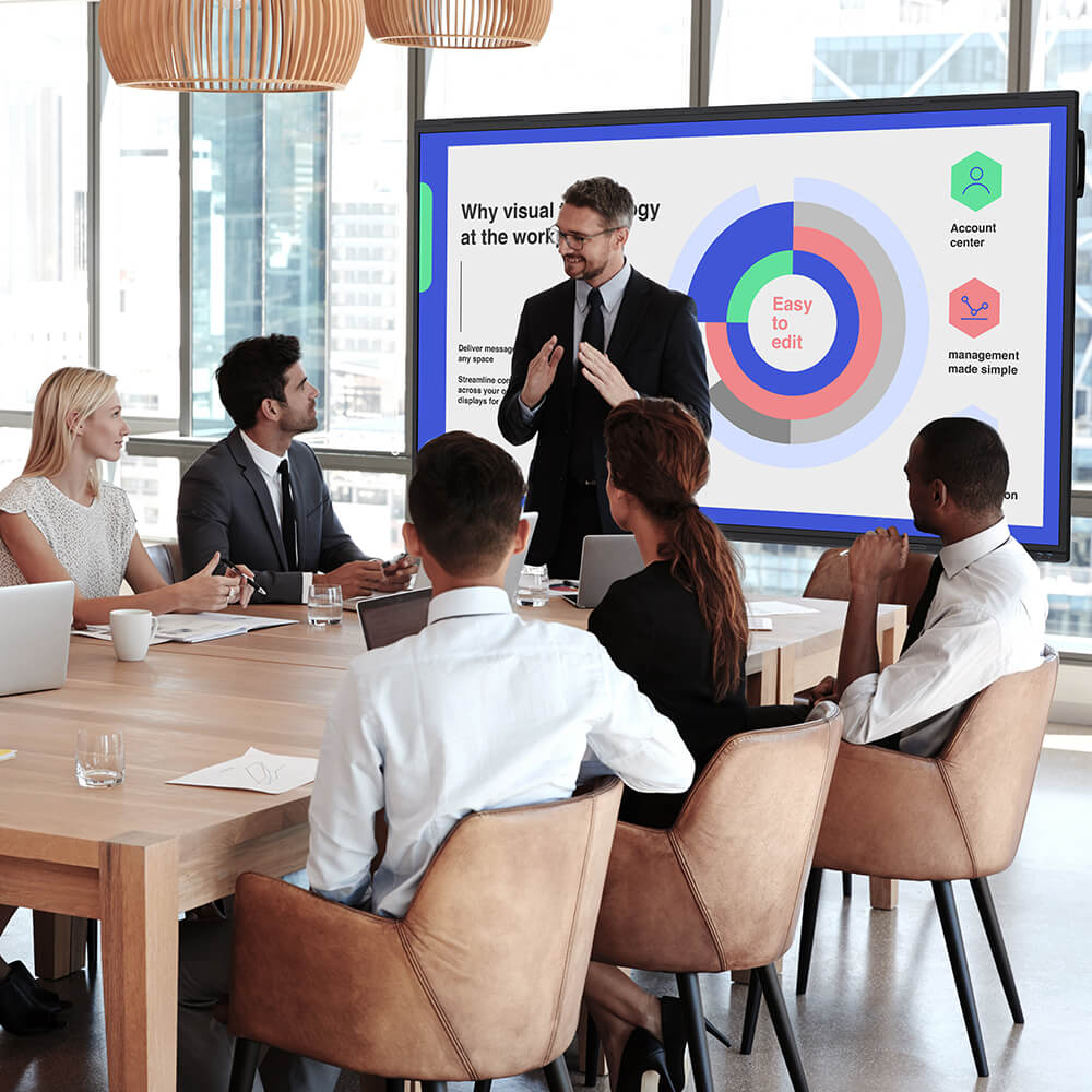 Professional team in a modern office attending a business meeting while a presenter explains data visualizations projected on a large screen using a projector — ideal for workplace collaboration and corporate presentations.