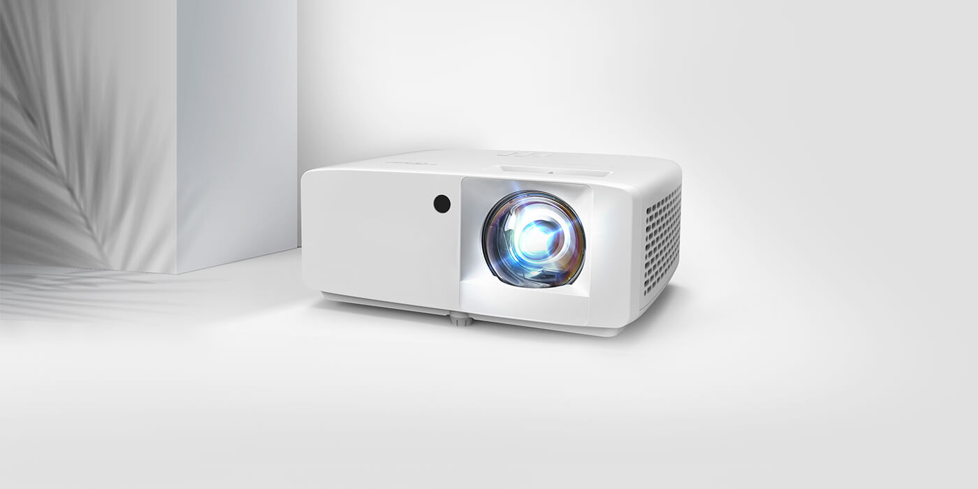Modernised image in a white room with a  shadow of a leaf to the left. And front centre of the image is an Optoma eco-friendly projector with the words above it that say 'Designed for Sustainability'. 