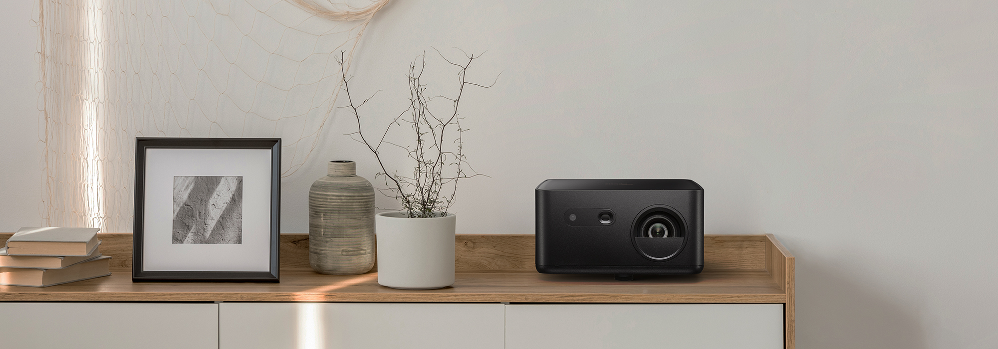 Compact Photon Life 4K UHD projector on furniture demonstrating portability and design