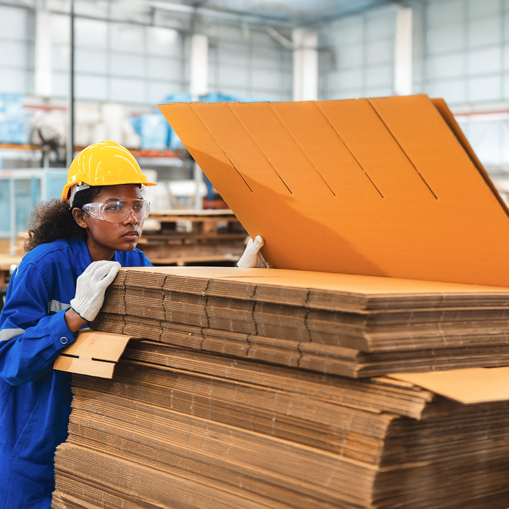 Factory worker in safety gear operating industrial equipment to reduce waste and improve manufacturing efficiency in sustainable production facility