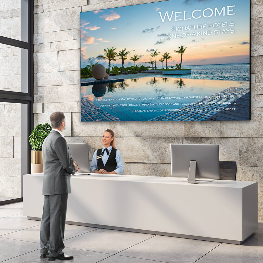 A modern reception area with a large LED screen behind teh desk that has a visual digital image of a beach and palm trees.